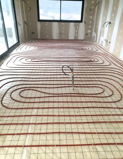 Pose de tubes de chauffage au sol sur isolant avant le coulage de la chape fluide, dans toute la vallée de l'Arve